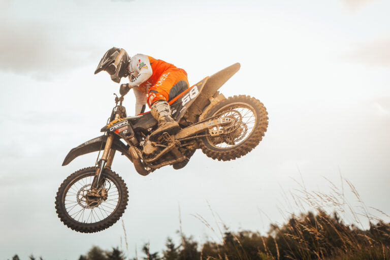 Motocross-Fahrer beim Sprung – Sponsoring im Motorsport zeigt sich auf Bikes und Ausrüstung.