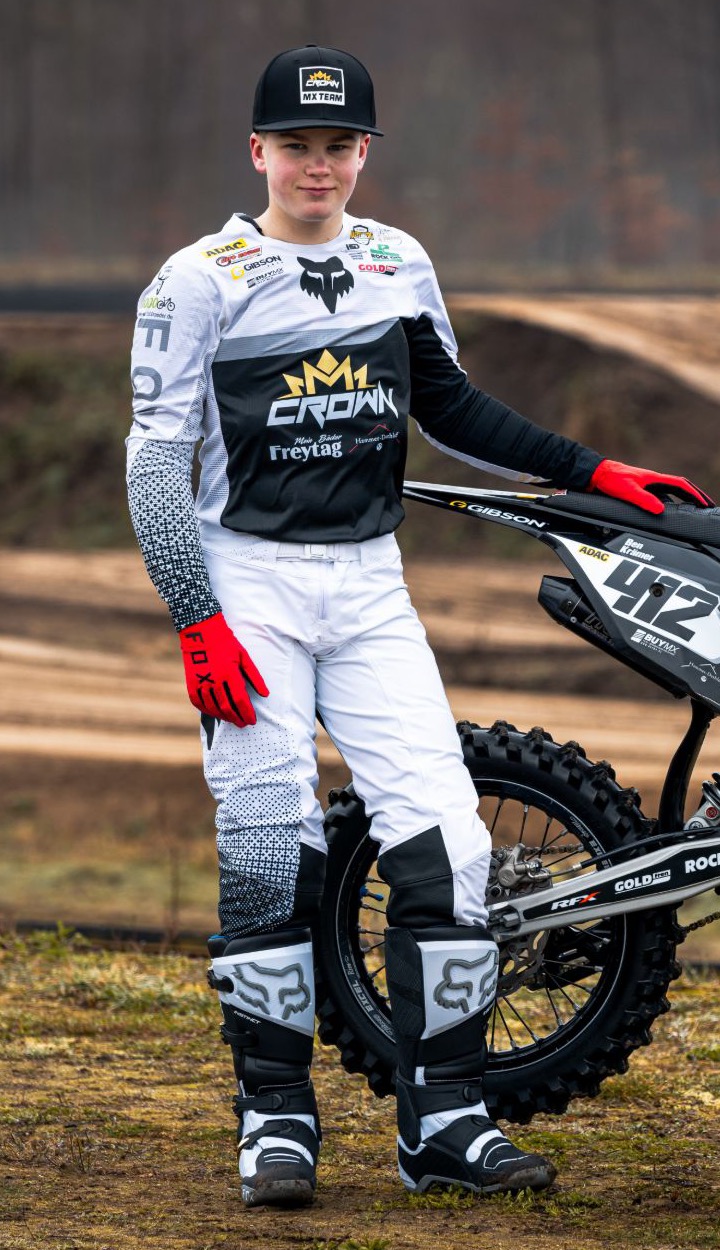 Crown-MX-Fahrer in der Renncombo neben seinem Bike